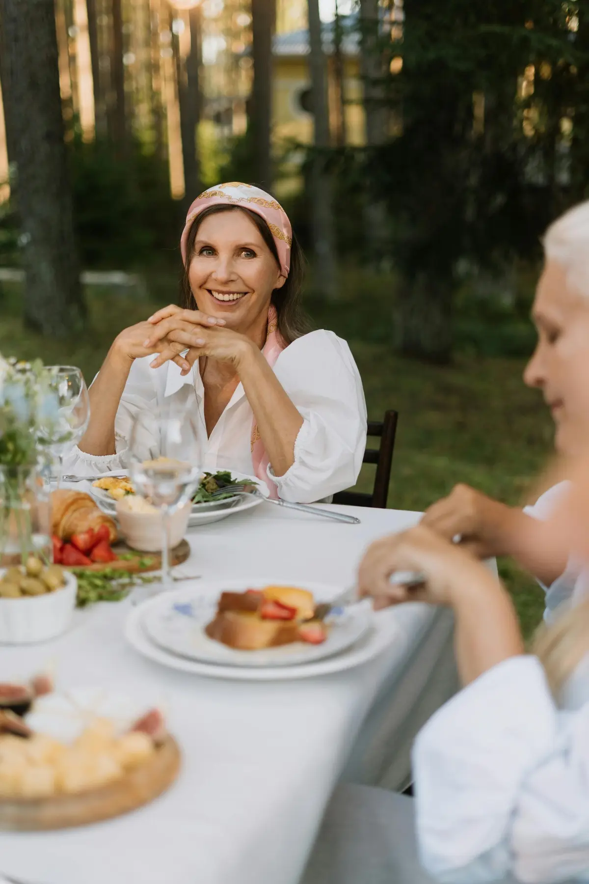 A traveler smiling at a long lunch table in the woods