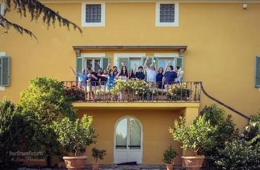 An extended family waving from a Tuscan villa balcony